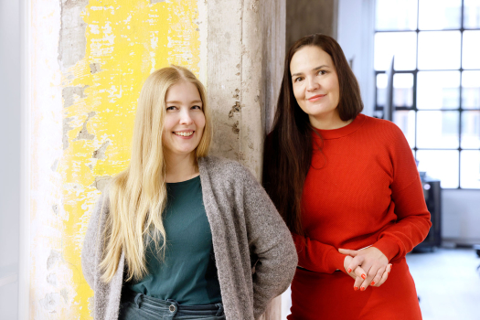 Siili solutionsin luottamushenkilö Maija Apunen ja henkilöstöjohtaja Taru Salo seisovat vierekkäin toimistossa ja hymyilevät.